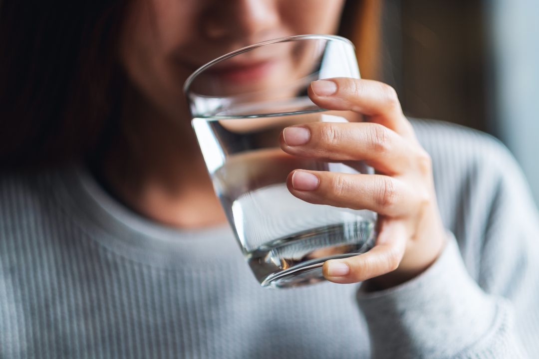 what not to do after iv drip. Closeup image of a woman holding a glass of water to drink