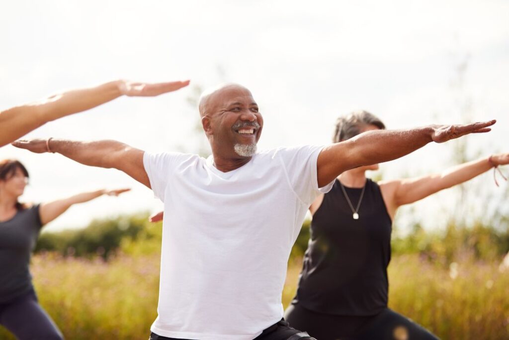 group of mature men and women in class at outdoor yoga retreat