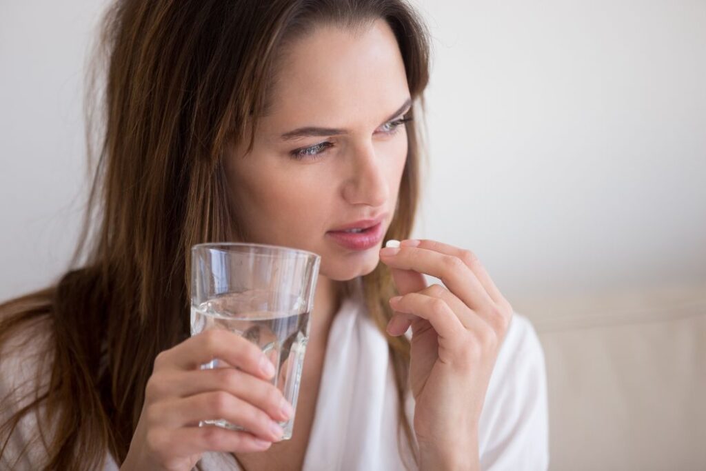 woman looking sick drinking a pill