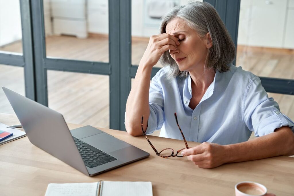 elderly woman stressed  in front of a laptop