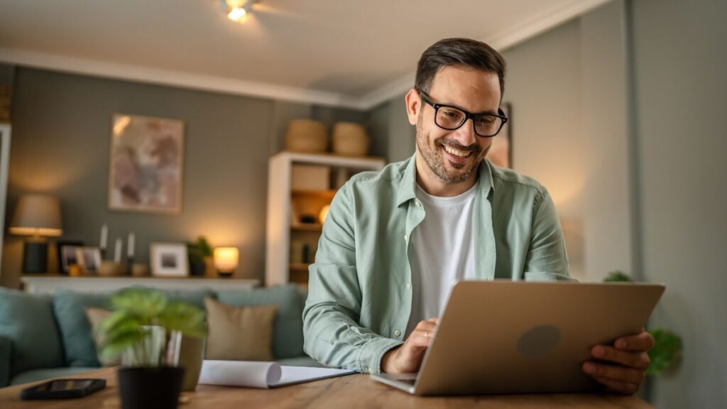 Man smiling while looking at the screen of his laptop 